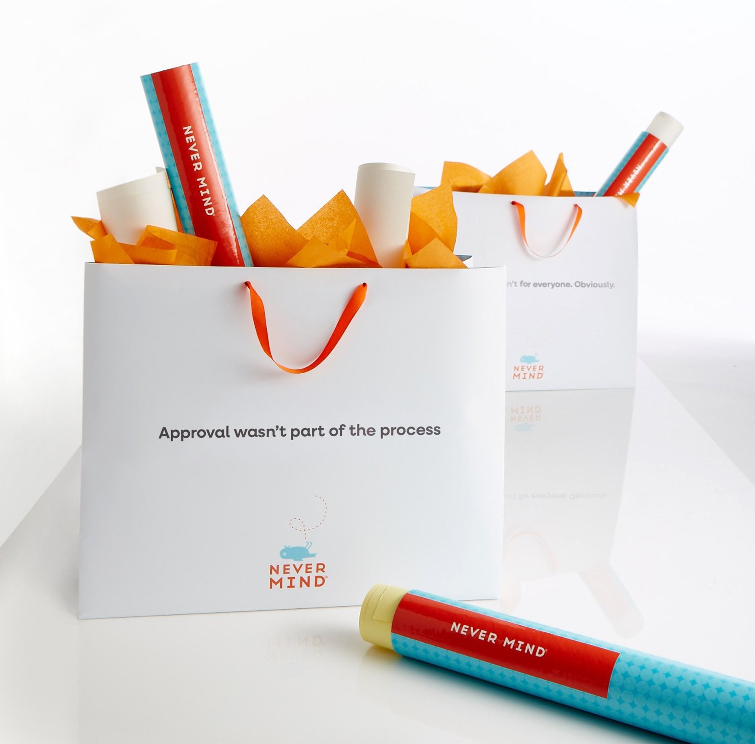 Never Mind shopping bags reading Approval wasn’t part of the process, with poster tubes and orange tissue paper
