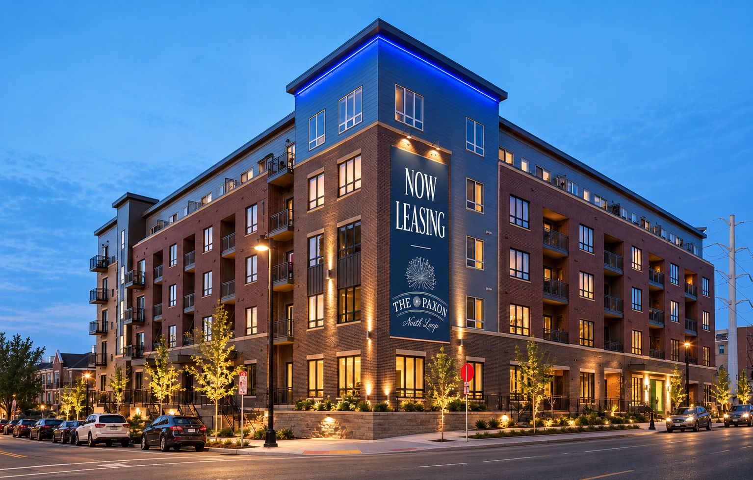 The Paxon apartment building at dusk with a Now Leasing banner