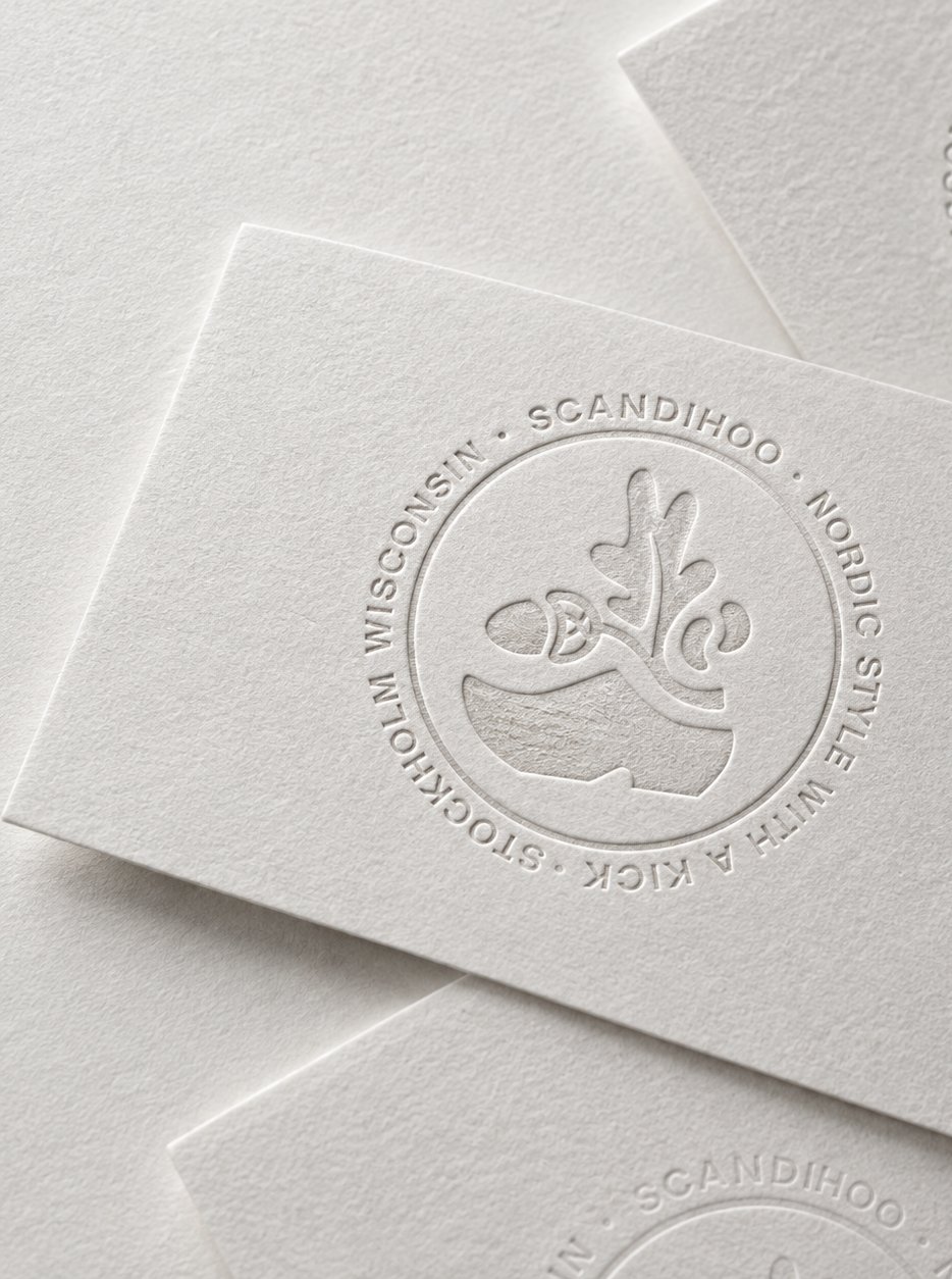 White cards blind-embossed with the round Scandihoo badge