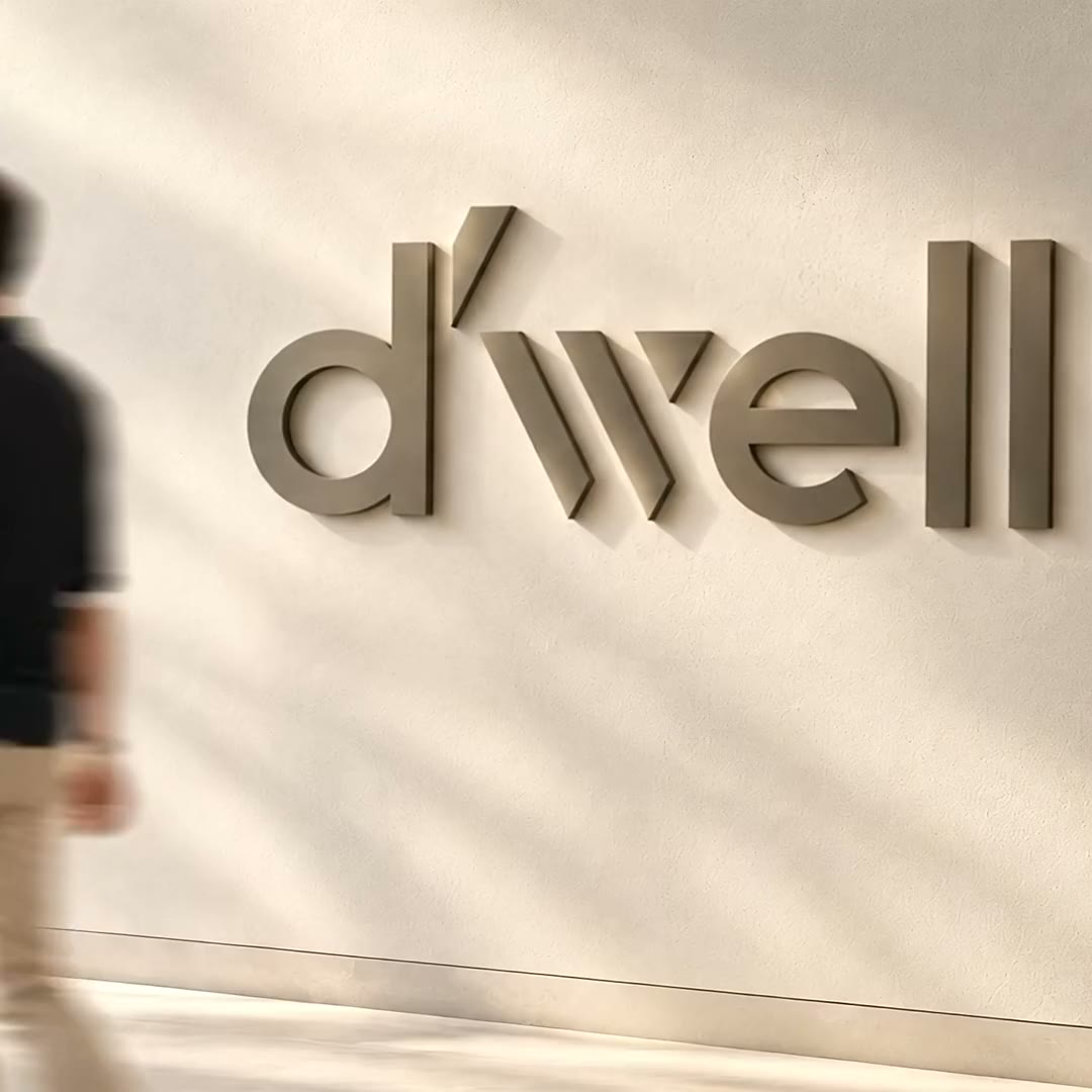 The D’well logo on a lobby wall as a man walks past