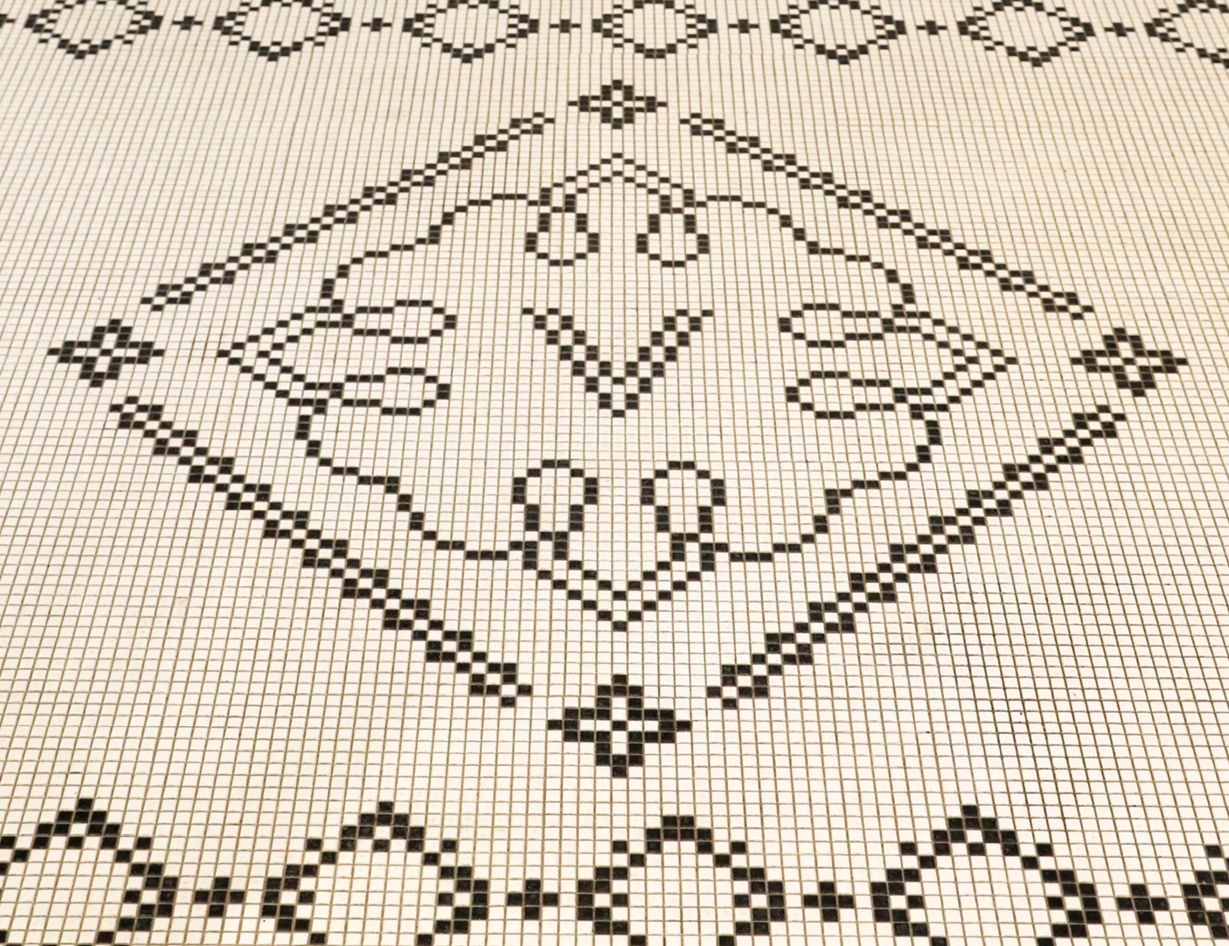 A mosaic tile floor with the V logo pattern